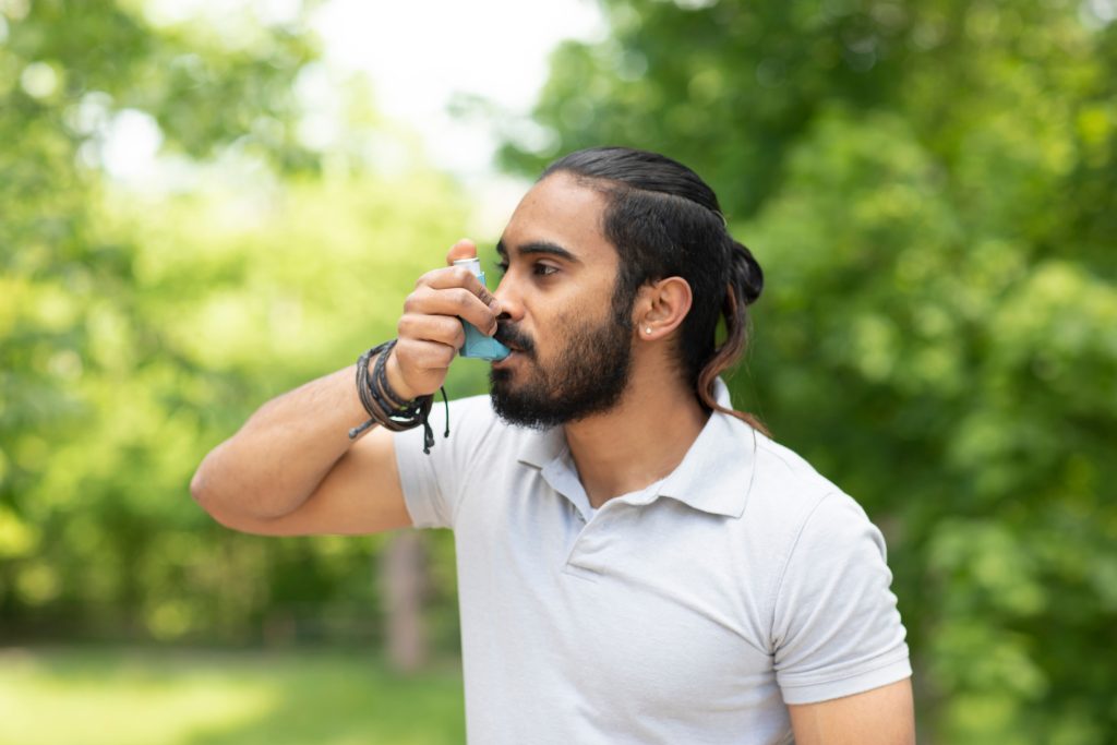 Man using inhaler outdoors in park